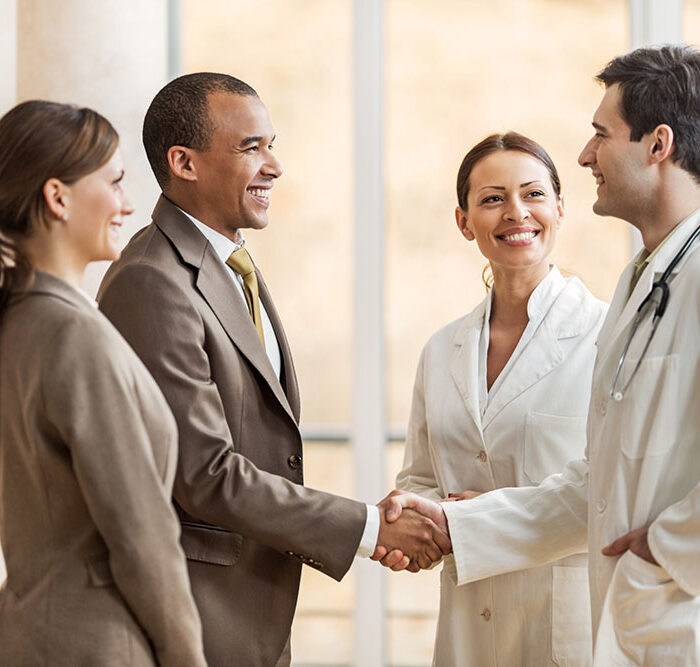 Business people collaborating with doctors. African American businessman shaking hands with a male doctor.