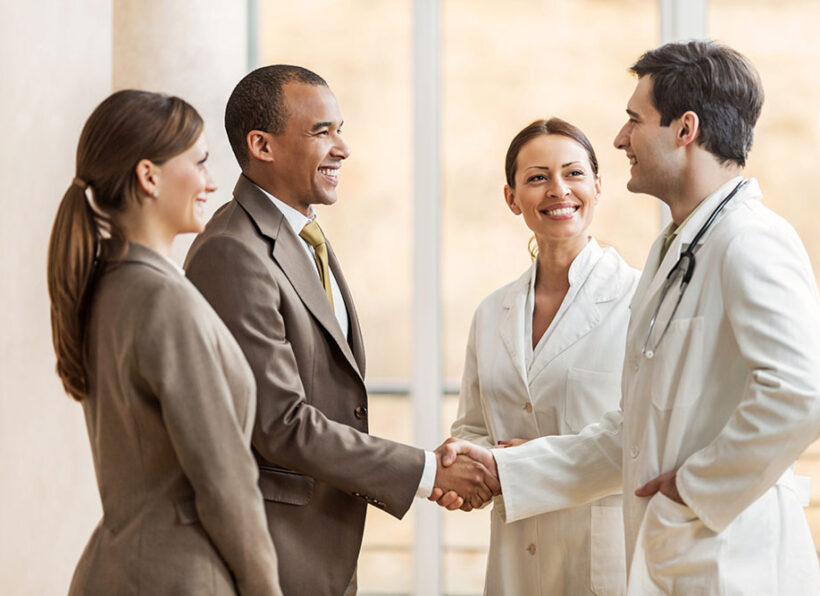 Business people collaborating with doctors. African American businessman shaking hands with a male doctor.