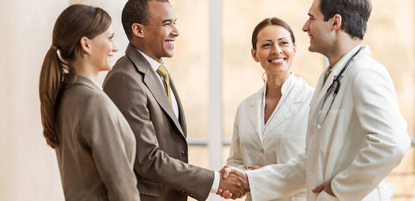 Business people collaborating with doctors. African American businessman shaking hands with a male doctor.