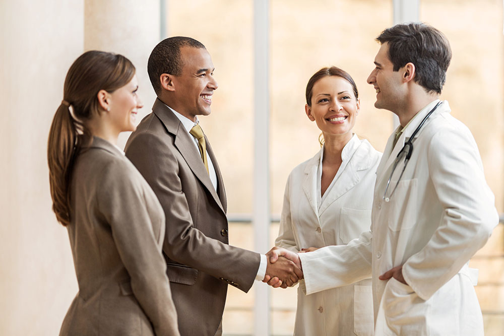 Business people collaborating with doctors. African American businessman shaking hands with a male doctor.