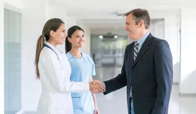 Doctor greeting health insurance agent with a handshake Doctor greeting health insurance agent with a handshake at the hospital