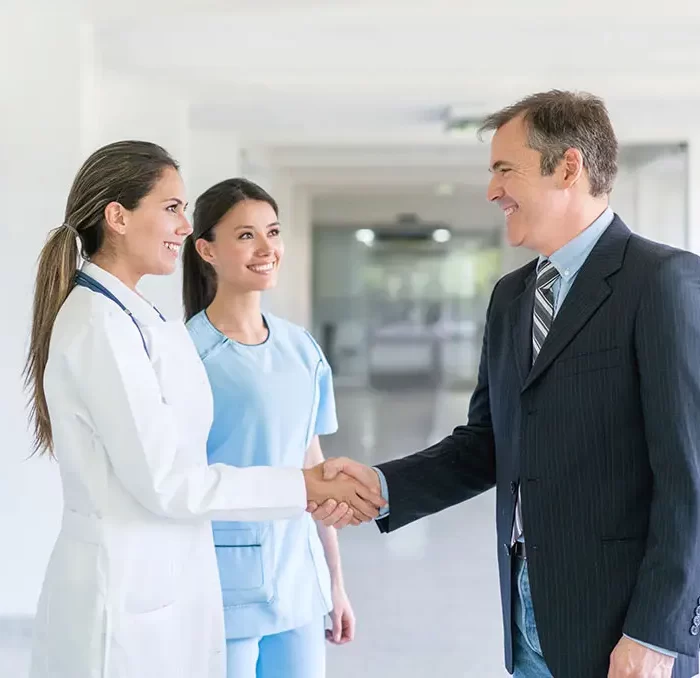 Doctor greeting health insurance agent with a handshake at the hospital