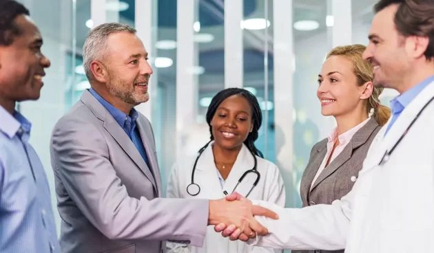 Mature businessman shaking hands with a doctor in the hospital. Happy business people and doctors came to an agreement.