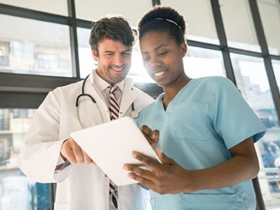 Nurse and doctor looking at the information of a patient on a digital tablet smiling Nurse and doctor looking at the information of a patient on a digital tablet both looking very happy and smiling