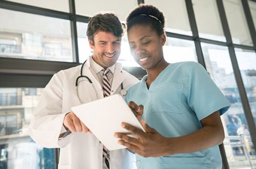 Nurse and doctor looking at the information of a patient on a digital tablet smiling Nurse and doctor looking at the information of a patient on a digital tablet both looking very happy and smiling